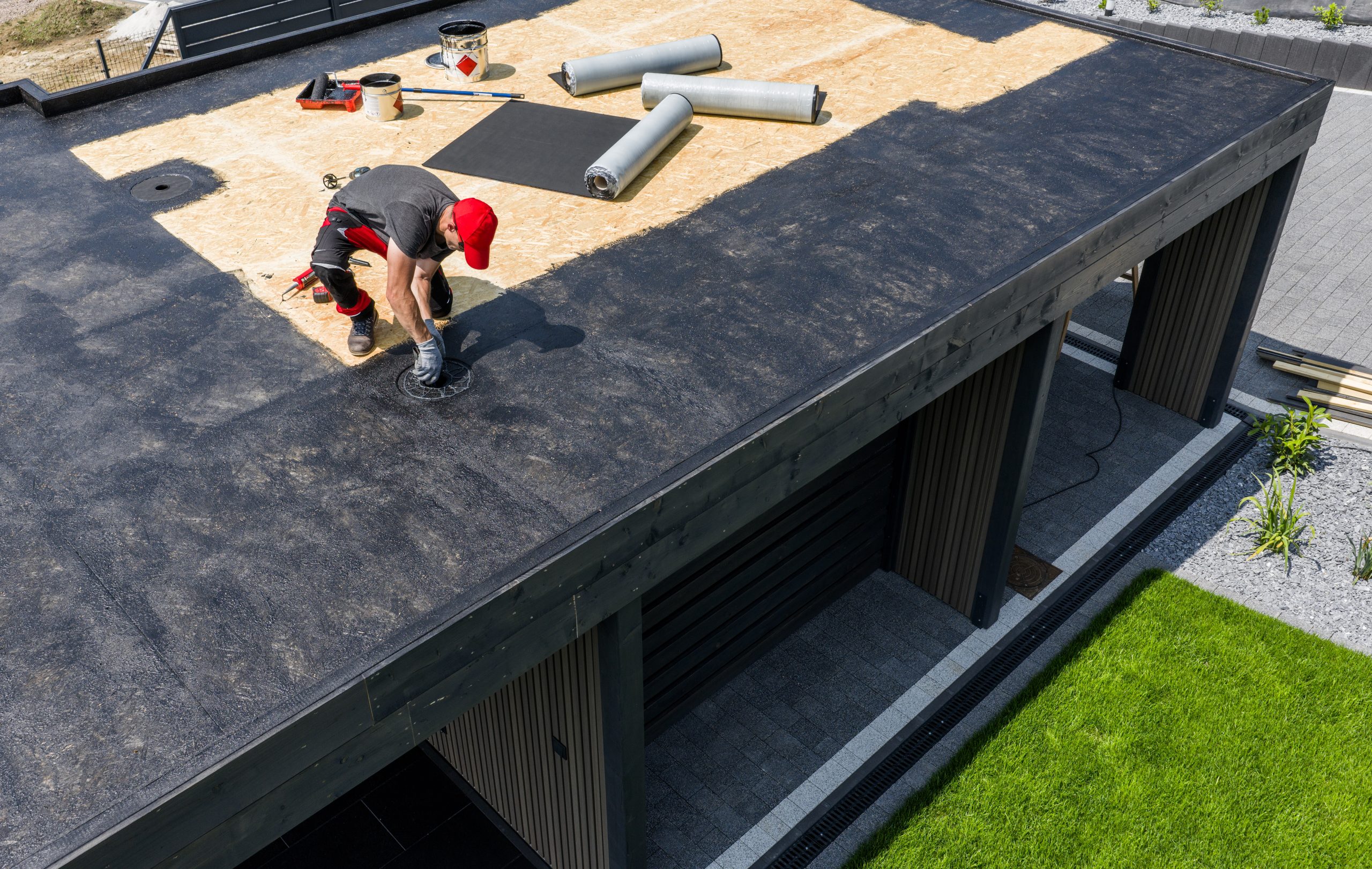 Construction Worker Applying EPDM Roofing Material on Modern House During Daytime