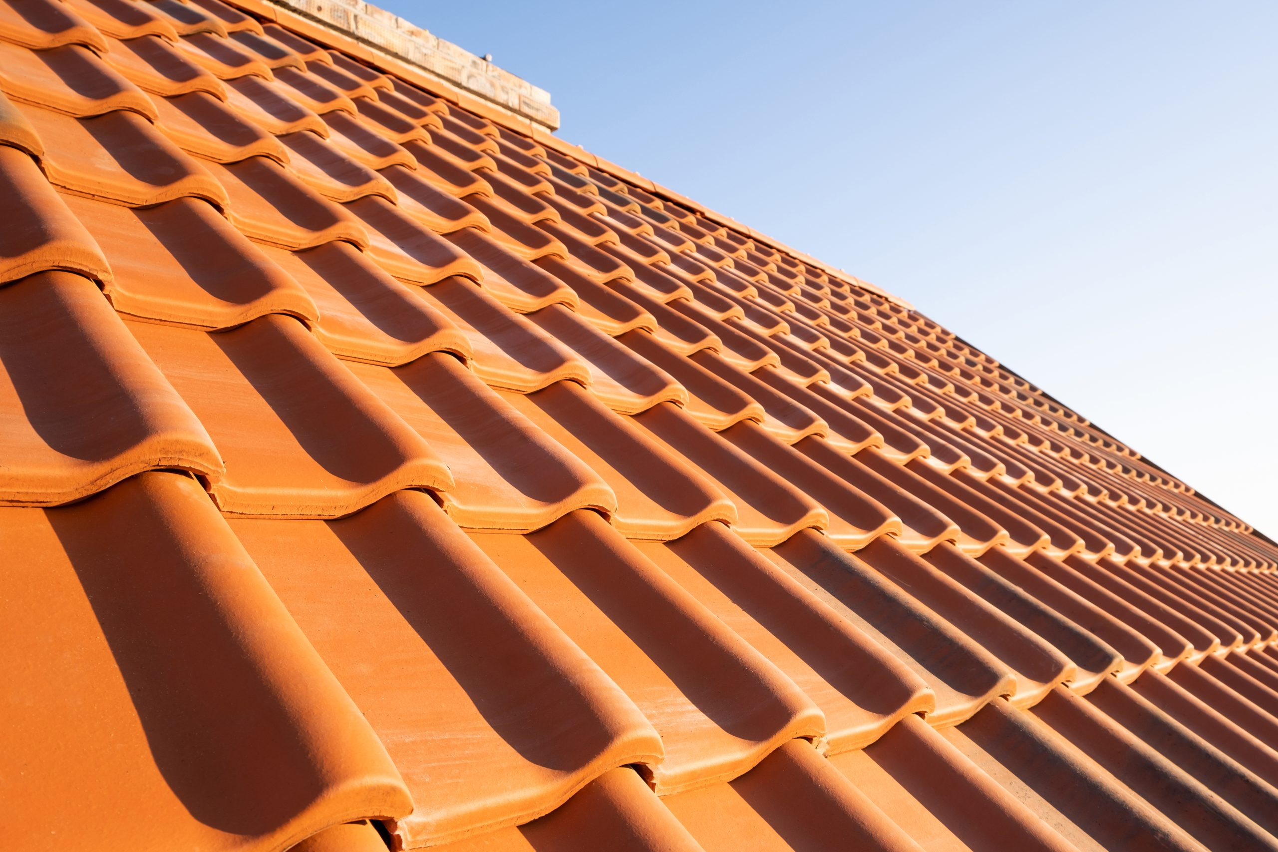 Overlapping rows of yellow ceramic roofing tiles covering residential building roof.